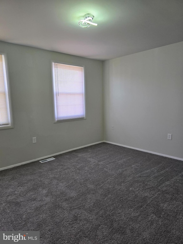 unfurnished room with dark colored carpet