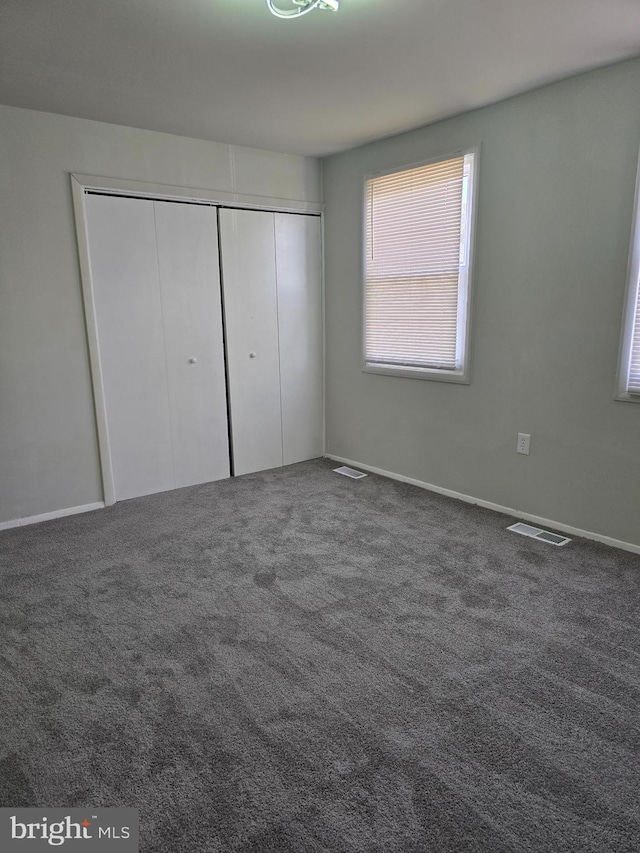 unfurnished bedroom featuring dark carpet and a closet