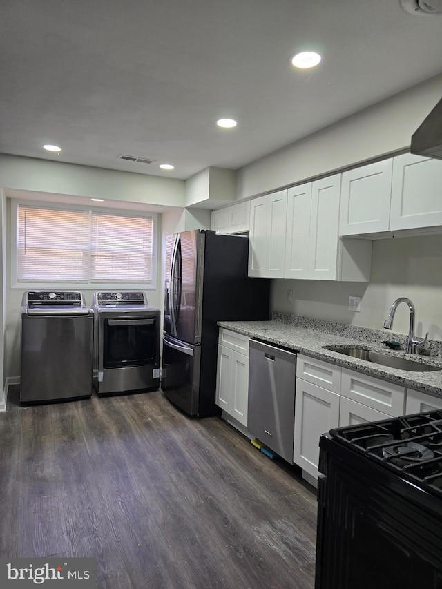 kitchen featuring dark wood-type flooring, sink, appliances with stainless steel finishes, independent washer and dryer, and white cabinets