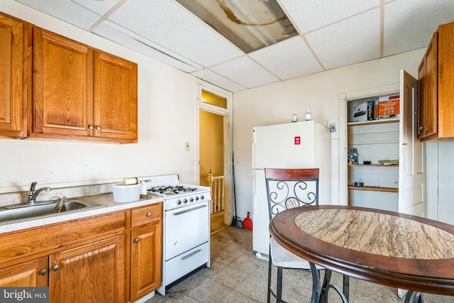 kitchen featuring a drop ceiling, white appliances, and sink