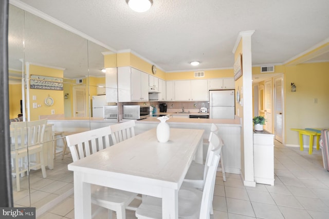 dining space featuring light tile patterned flooring, a textured ceiling, and crown molding