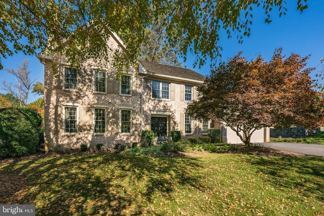 colonial home with a garage and a front lawn