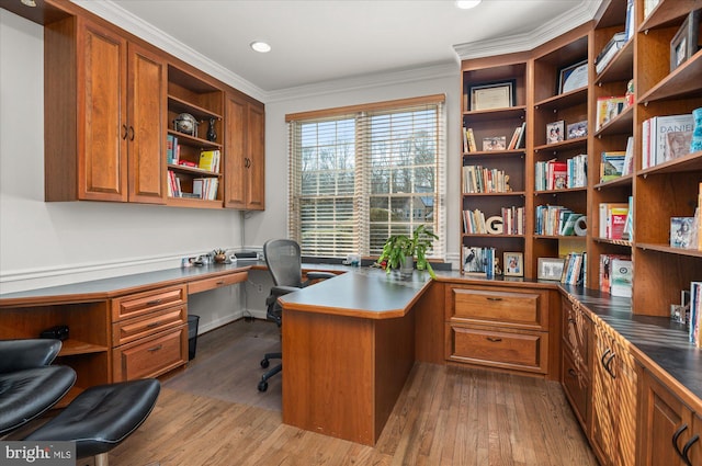 home office with ornamental molding, wood-type flooring, and built in desk