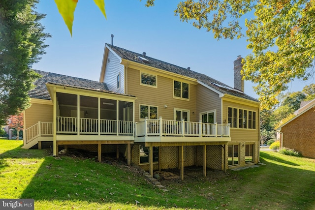 rear view of house featuring a yard, a sunroom, and a deck