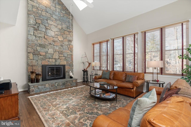 living room featuring a skylight, a fireplace, high vaulted ceiling, and dark hardwood / wood-style floors