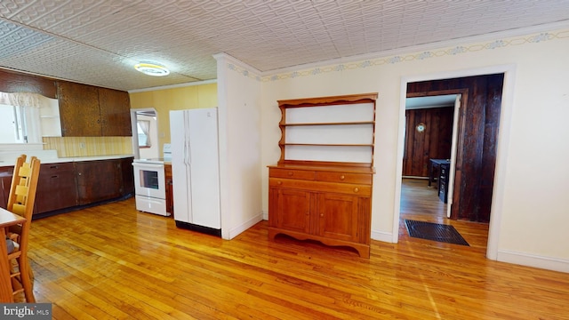 kitchen featuring light wood-type flooring, white appliances, ornamental molding, and light countertops