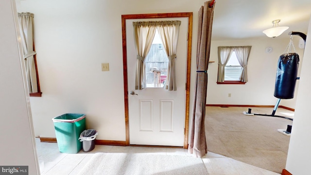 doorway to outside with light colored carpet and a wealth of natural light