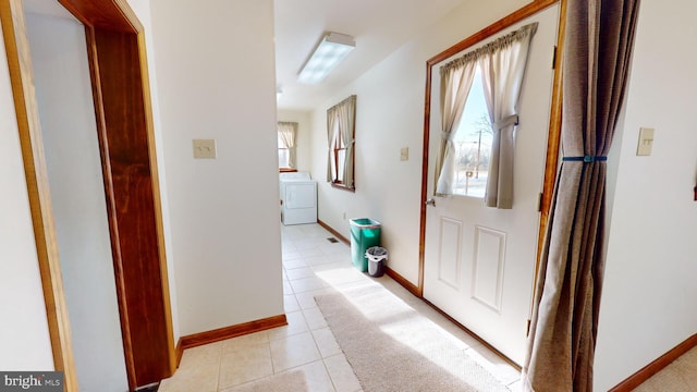 hallway with washer / dryer, plenty of natural light, and light tile patterned floors