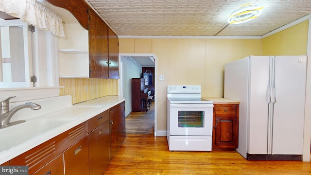 kitchen with light wood-type flooring, sink, and white appliances