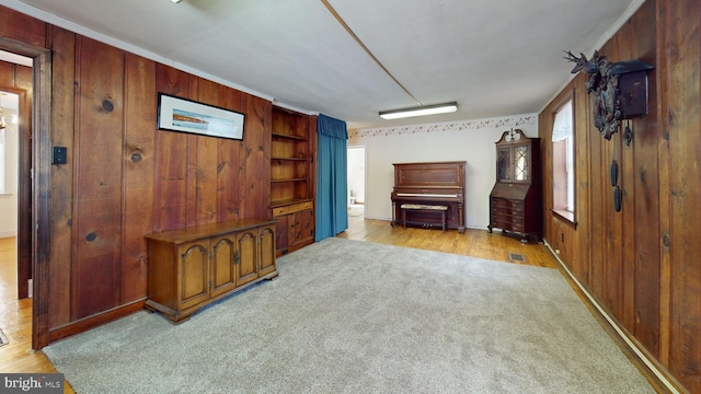 unfurnished living room with wooden walls and light colored carpet