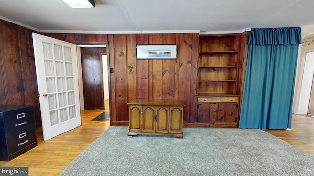 bedroom featuring crown molding, wooden walls, and light wood-type flooring