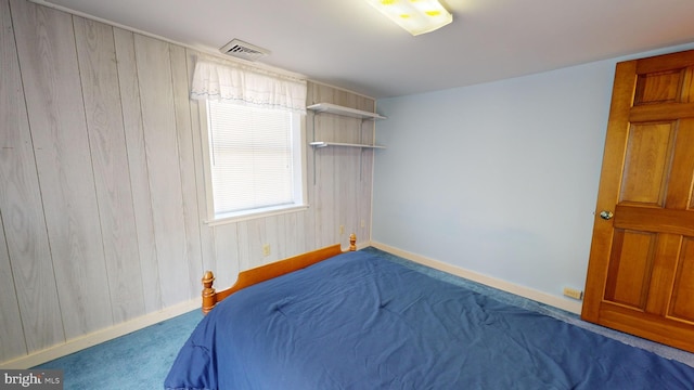 bedroom featuring wood walls, baseboards, visible vents, and carpet flooring