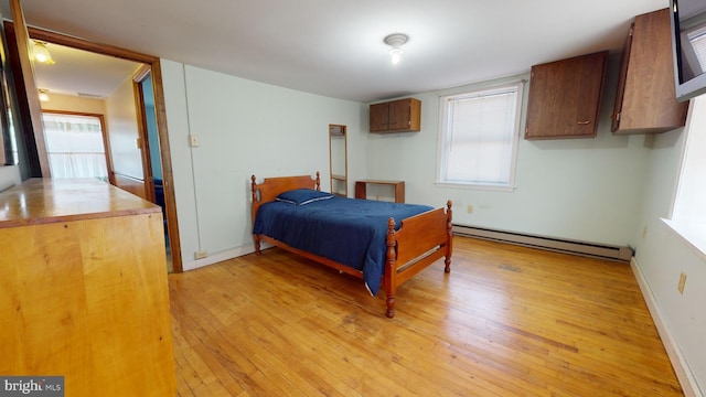 bedroom with a baseboard heating unit and light hardwood / wood-style floors