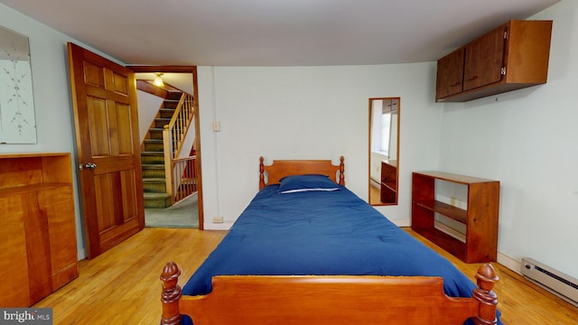 bedroom featuring a baseboard heating unit, a closet, and light wood-style flooring