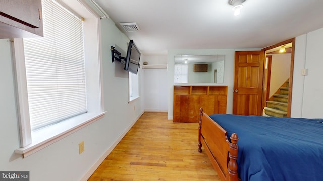 bedroom with light wood-style floors, visible vents, and baseboards