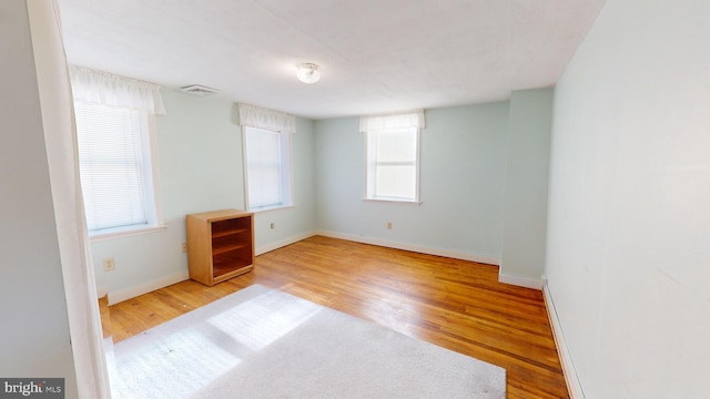 spare room with baseboards, visible vents, and wood finished floors