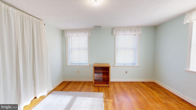 spare room featuring baseboards, visible vents, and hardwood / wood-style floors