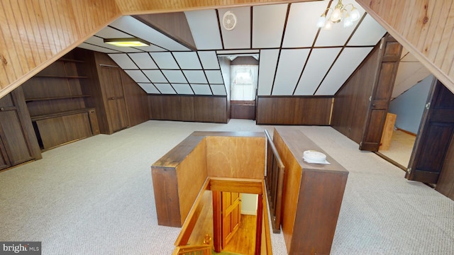 bonus room with lofted ceiling, a notable chandelier, wooden walls, and light colored carpet