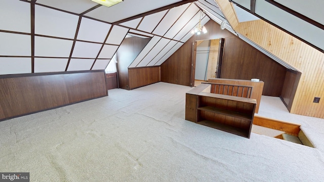 additional living space with lofted ceiling, wood walls, and light colored carpet