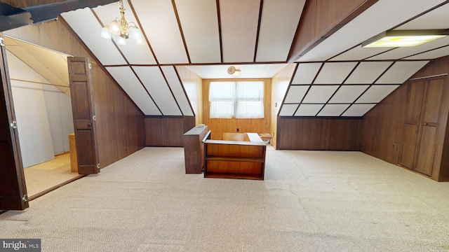 additional living space featuring light carpet, wooden walls, an inviting chandelier, and vaulted ceiling