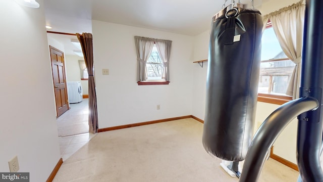 workout room with light carpet, washer / clothes dryer, and baseboards