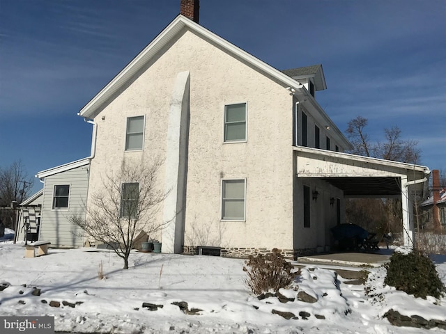 view of snowy exterior featuring a carport