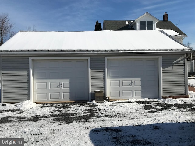 snow covered garage featuring a detached garage