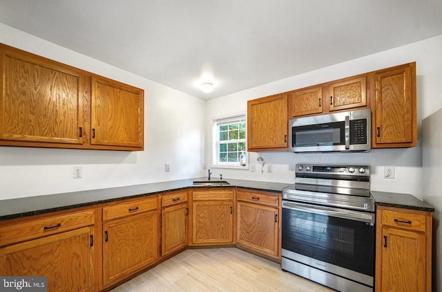 kitchen featuring appliances with stainless steel finishes, light wood-type flooring, and sink