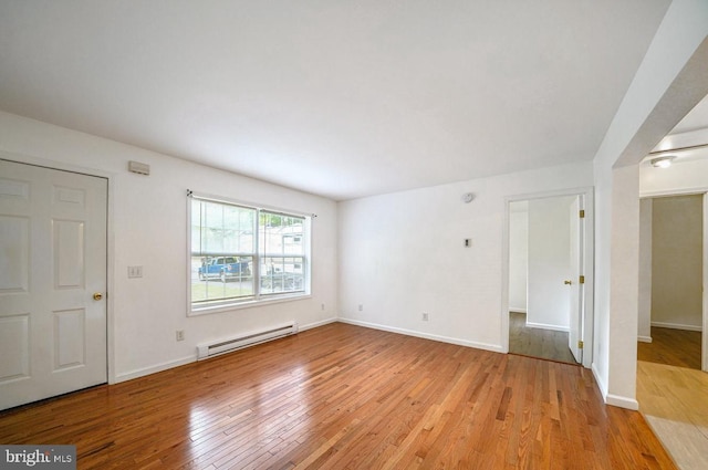 unfurnished room with light wood-type flooring and baseboard heating