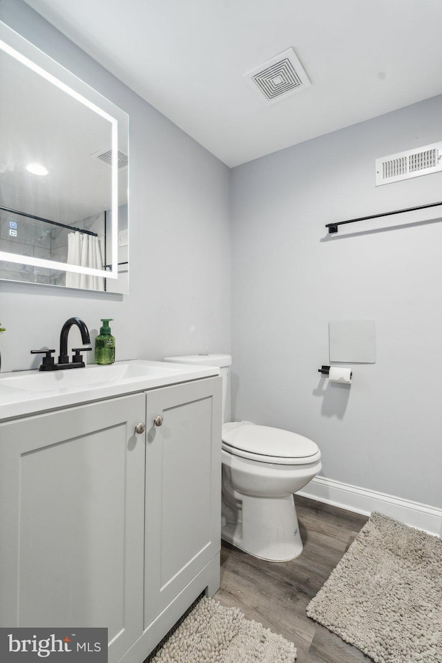 bathroom featuring a shower with curtain, vanity, hardwood / wood-style flooring, and toilet