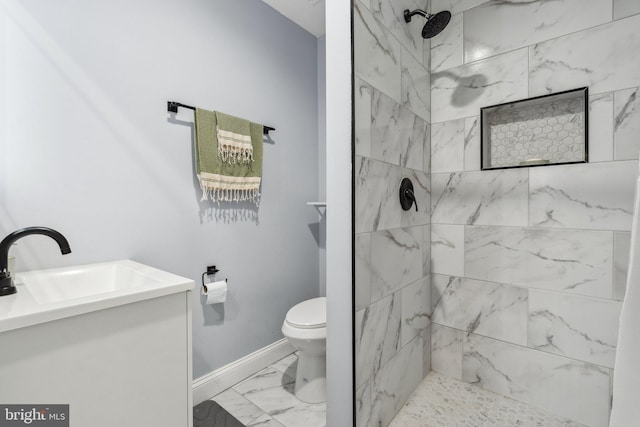 bathroom featuring tiled shower, vanity, and toilet