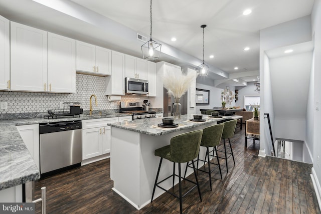 kitchen with a kitchen island, dark hardwood / wood-style flooring, white cabinetry, and appliances with stainless steel finishes