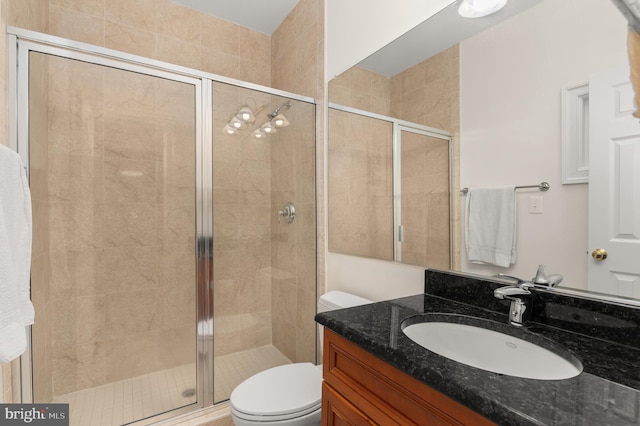 bathroom featuring an enclosed shower, vanity, and toilet