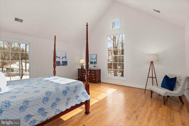 bedroom featuring multiple windows, light hardwood / wood-style flooring, and high vaulted ceiling