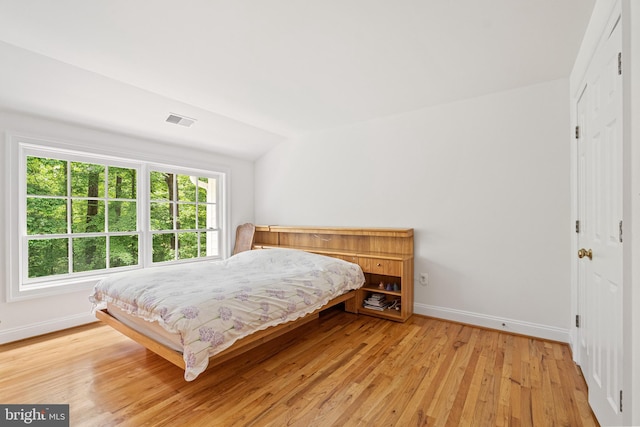 bedroom with lofted ceiling and light wood-type flooring