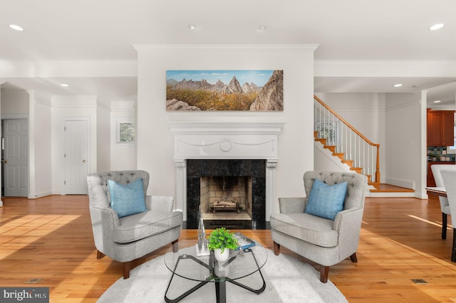 living room with ornamental molding, a premium fireplace, and light wood-type flooring