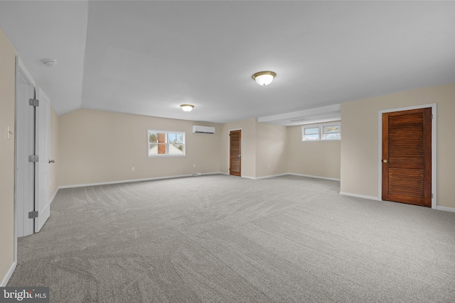 unfurnished room with vaulted ceiling, a wall mounted AC, and light colored carpet