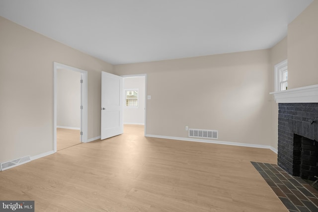 unfurnished living room featuring a brick fireplace and light hardwood / wood-style flooring