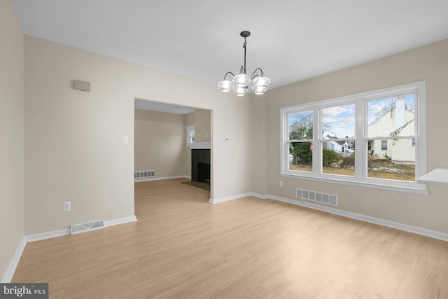 unfurnished dining area with light hardwood / wood-style flooring and a chandelier