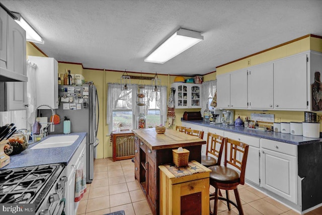 kitchen featuring light tile patterned floors, a textured ceiling, white cabinetry, and a kitchen breakfast bar