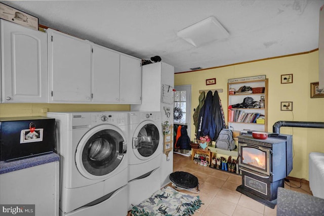 laundry area with washing machine and clothes dryer, a wood stove, cabinets, and ornamental molding