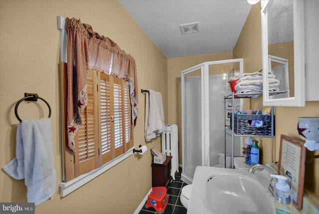 bathroom with tile patterned flooring, radiator, a shower with shower door, and sink