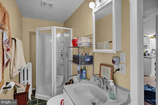 bathroom with radiator, a shower with door, vanity, and tile patterned flooring