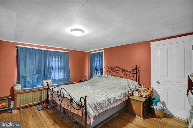 bedroom with hardwood / wood-style floors and radiator heating unit