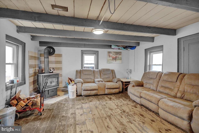 living room featuring beam ceiling, a wood stove, and hardwood / wood-style flooring