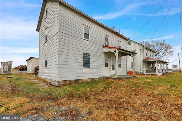 rear view of house featuring a lawn and covered porch