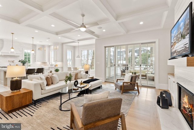 living room featuring a premium fireplace, a wealth of natural light, and coffered ceiling