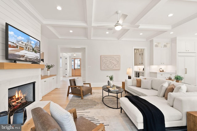 living room featuring ceiling fan, coffered ceiling, light hardwood / wood-style flooring, beamed ceiling, and a fireplace