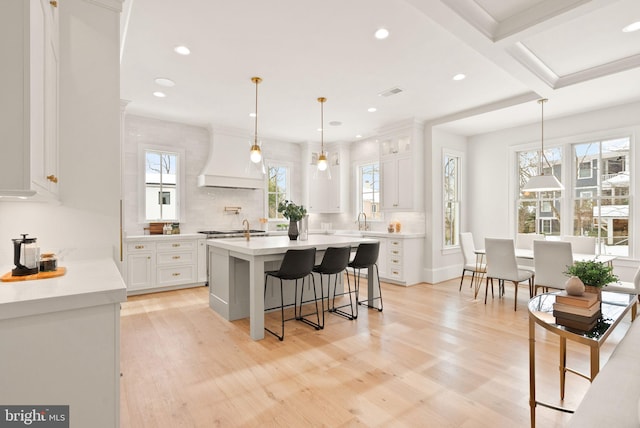 kitchen with white cabinetry, decorative light fixtures, and light wood-type flooring