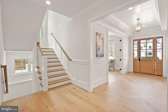 foyer with ornamental molding and an inviting chandelier